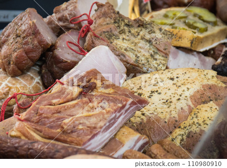 Fresh prepared smoked hams with spices on market stall 110980910