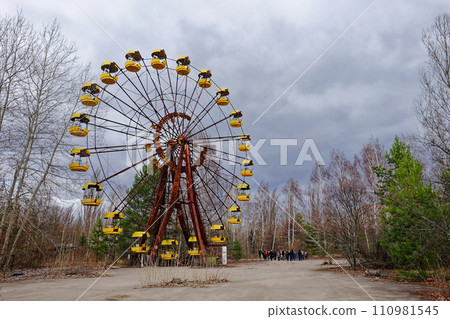 An old Ferris wheel with yellow gondolas is surrounded by leafless trees. An old Ferris wheel with yellow gondolas is surrounded by leafless trees. 110981545