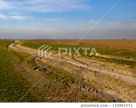 The image captures a serene rural setting featuring fields and a meandering path. The image captures a serene rural setting featuring fields and a meandering path. 110981551