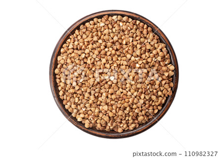 Green buckwheat grain in clay bowl isolated on white background, top view.  110982327