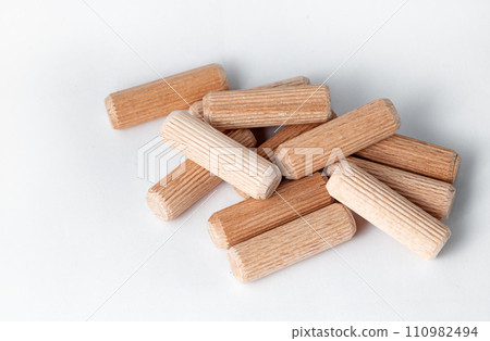 Pile of wooden dowels on the white background. 110982494