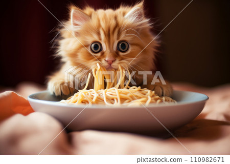 Hungry little red kitten eats heartily of pasta Hungry little red kitten eats heartily of pasta 110982671