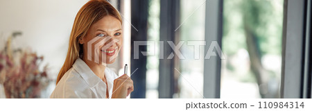 Smiling business woman working on laptop, making notes in cozy coworkign space interior Smiling business woman working on laptop, making notes in cozy coworkign space interior 110984314
