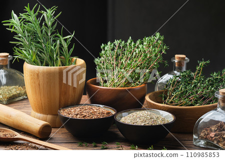 Bowls of dry different healing plants and fresh green medicinal herbs - rosemary and thyme. Bottles of dry medicinal herb for making tinctures or infusions. Alternative herbal medicine. Bowls of dry different healing plants and fresh green medicinal herbs - rosemary and thyme. Bottles of dry medicinal herb for making tinctures or infusions. Alternative herbal medicine. 110985853