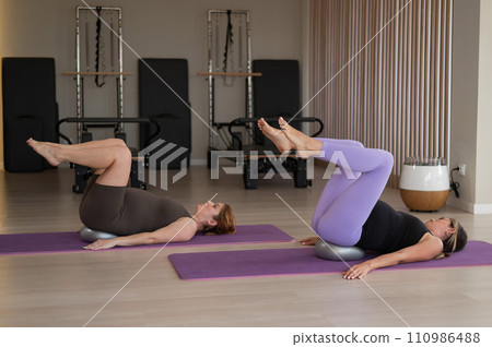 Two pregnant women doing Pilates with special small fit balls. Two pregnant women doing Pilates with special small fit balls. 110986488