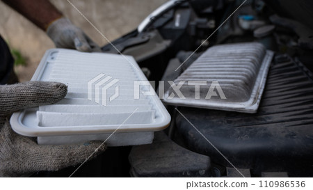 The master changes the air filter in the car engine.  110986536