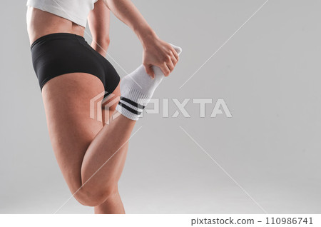 Faceless woman stretching her quadriceps on a white background. Faceless woman stretching her quadriceps on a white background. 110986741