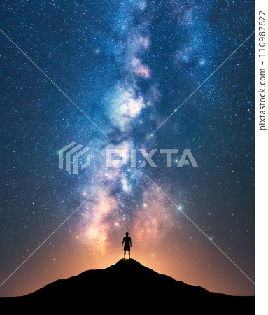 Milky Way and sporty man on mountain peak at starry night 110987822