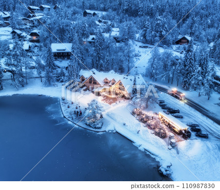 Aerial view of illuminated houses in snowy village at night Aerial view of illuminated houses in snowy village at night 110987830