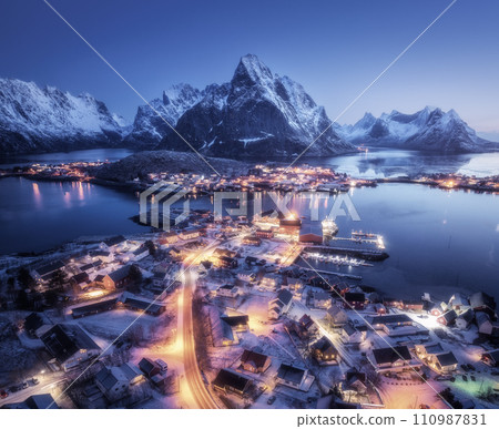 Aerial view of snowy village, city lights, sea, mountain at night Aerial view of snowy village, city lights, sea, mountain at night 110987831
