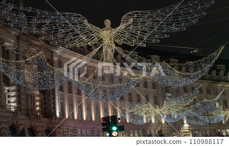 Flying angel Christmas decoration led lights display. Dramatic view of the traditional Christmas decoration lights hanging above Regent Street during dusk. Flying angel Christmas decoration led lights display. Dramatic view of the traditional Christmas decoration lights hanging above Regent Street during dusk. 110988117