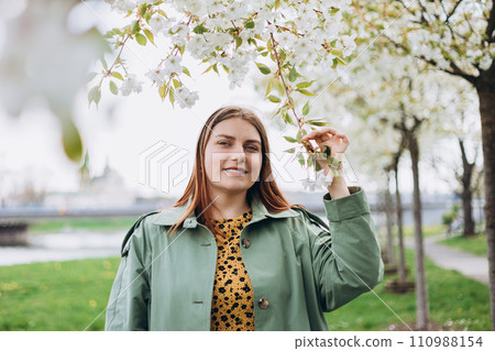Young woman enjoying scent in blooming spring garden. Spring girl photo. Portrait of tender woman at sakura flowers background. Hanami celebration in blooming garden. Young woman enjoying scent in blooming spring garden. Spring girl photo. Portrait of tender woman at sakura flowers background. Hanami celebration in blooming garden. 110988154