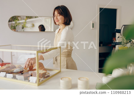 Pretty female waitress hands putting a delicious dessert on a plate standing behind bar counter Pretty female waitress hands putting a delicious dessert on a plate standing behind bar counter 110988213