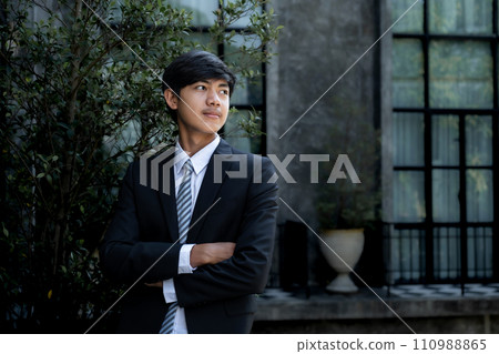 Young businessman financier investors stand with a luxurious black hotel building in the background 110988865