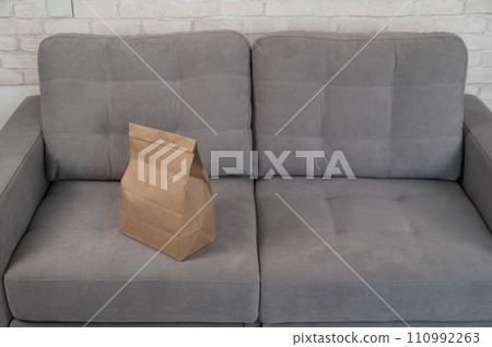 Kraft paper bag with food delivery on gray sofa.  110992263