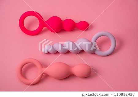 A set of three silicone anal beads of various shapes and sizes on an pink background. A set of three silicone anal beads of various shapes and sizes on an pink background. 110992423