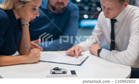Happy caucasian couple signs a contract for the purchase of a car salon. 110992602