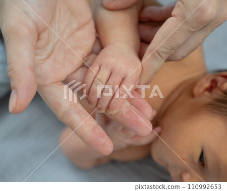 A newborn boy holds his mother's finger. Close-up of hands. A newborn boy holds his mother's finger. Close-up of hands. 110992653