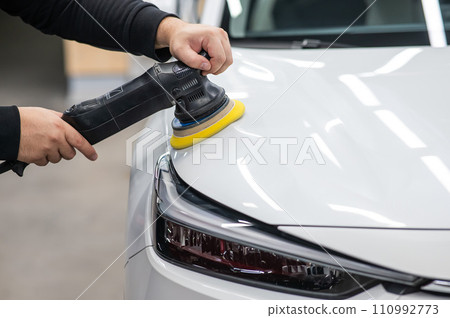 Process of polishing white car hood surface using orbital polishing machine. Process of polishing white car hood surface using orbital polishing machine. 110992773