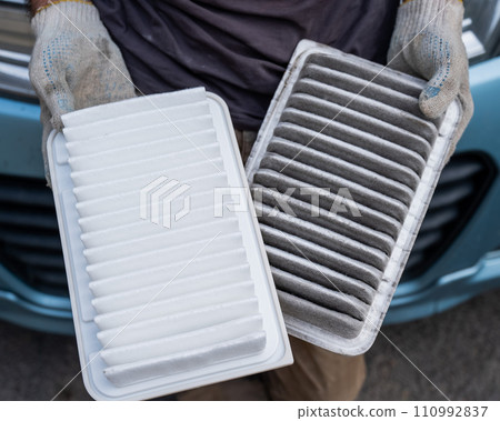 The master changes the air filter in the car engine. The master changes the air filter in the car engine. 110992837