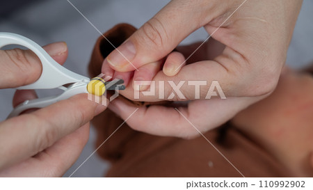 Mom cuts her newborn son's fingernails with small children's scissors. Mom cuts her newborn son's fingernails with small children's scissors. 110992902