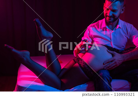 A man with a mistress on his knees holds an anal plug in the bedroom. 110993321