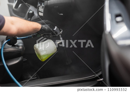 A man does professional dry cleaning of a car interior.  110993332