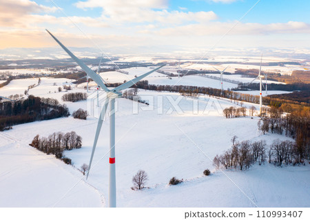 Winter meadow with wind turbines generating electricity. Green energy concept.  110993407
