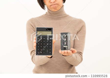 一名中年婦女拿著建築模型和計算器,憂心忡忡。 一名中年婦女拿著建築模型和計算器,憂心忡忡。 110993528