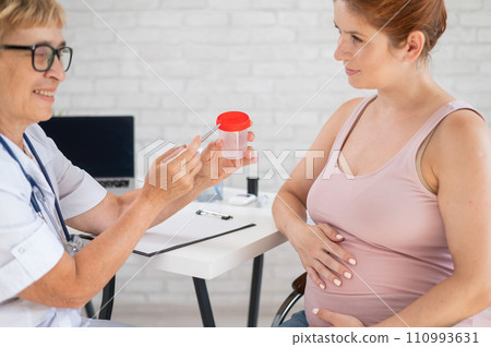 The doctor explains to a pregnant patient how to pass a urine test. 110993631