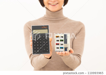 A middle-aged woman smiling while holding an apartment model and a calculator A middle-aged woman smiling while holding an apartment model and a calculator 110993965