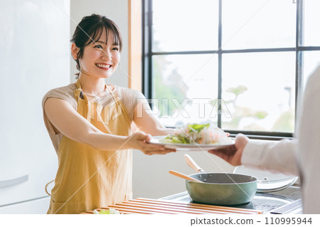 一個微笑的女人從廚房遞沙拉（家庭主婦、新婚夫婦、管家、家庭幫手） 110995944
