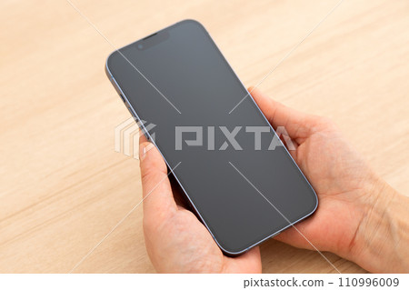 Hand of a middle-aged woman holding a smartphone Hand of a middle-aged woman holding a smartphone 110996009