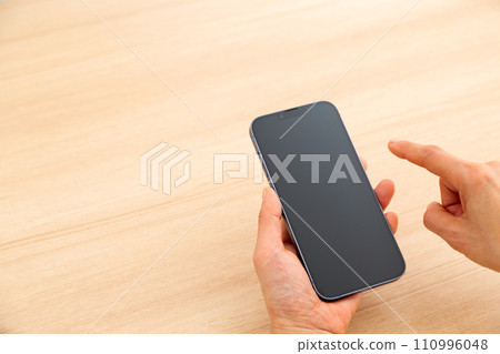 Hand of a middle-aged woman holding a smartphone 110996048