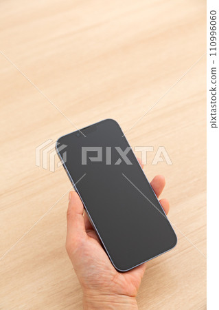Hand of a middle-aged woman holding a smartphone 110996060