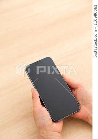 Hand of a middle-aged woman holding a smartphone 110996062