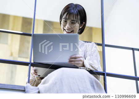 一位女士坐在室內橋上使用筆記型電腦 110996609