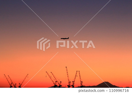 View of Mt. Fuji as seen from central Tokyo at sunset with a plane flying above in the orange sky View of Mt. Fuji as seen from central Tokyo at sunset with a plane flying above in the orange sky 110996716