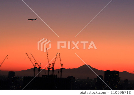 View of Mt. Fuji as seen from central Tokyo at sunset with a plane flying above in the orange sky View of Mt. Fuji as seen from central Tokyo at sunset with a plane flying above in the orange sky 110996718