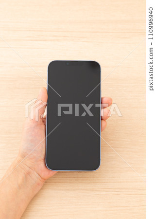 Hand of a middle-aged woman holding a smartphone 110996940
