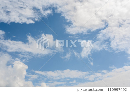 blue sky backdrop adorned with fluffy white clouds sets serene and open canvas. gentle dance of clouds complements vivid azure background, peaceful and harmonious celestial 110997492
