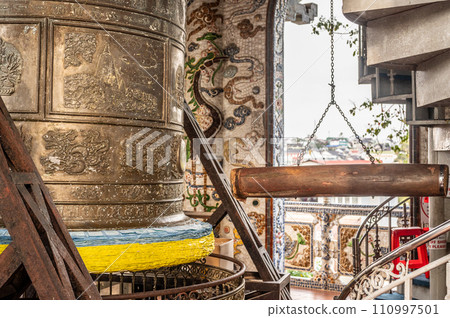 Asian temple, massive bell hangs silently, serene atmosphere of spiritual practice. Nearby, sturdy wooden log, poised for striking, represents ancient ritual of resonating sacred sound 110997501