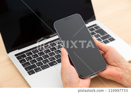 Hand of a middle-aged woman holding a smartphone 110997733