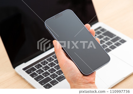 Hand of a middle-aged woman holding a smartphone Hand of a middle-aged woman holding a smartphone 110997736