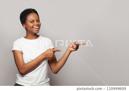 Attractive woman pointing finger at light gray studio wall banner background 110999609