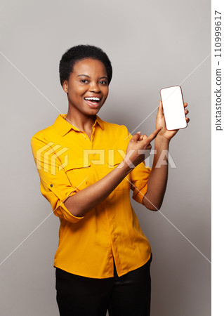 Student woman showing smartphone with empty blank screen display. Model in yellow shirt with phone Student woman showing smartphone with empty blank screen display. Model in yellow shirt with phone 110999617