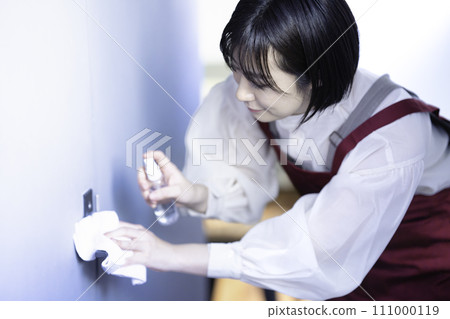 A woman in an apron disinfecting 111000119