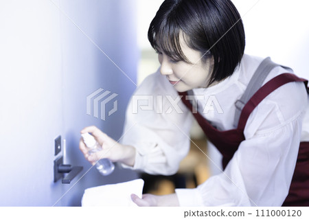 A woman in an apron disinfecting A woman in an apron disinfecting 111000120