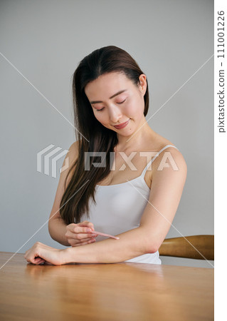 一名30多歲的女性用女士刮鬍刀剃掉手臂上的毛髮 一名30多歲的女性用女士刮鬍刀剃掉手臂上的毛髮 111001226