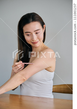 一名30多歲的女性用女士刮鬍刀剃掉手臂上的毛髮 111001237